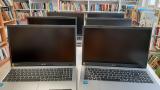 Na zdjęciu widać sześć laptopów na stoliku w tle regał z książkami