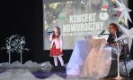 dziewczynka w czerwonej sukience na scenie, obok pan andrzej żółkoś, w tle baner z napisem koncert noworoczny