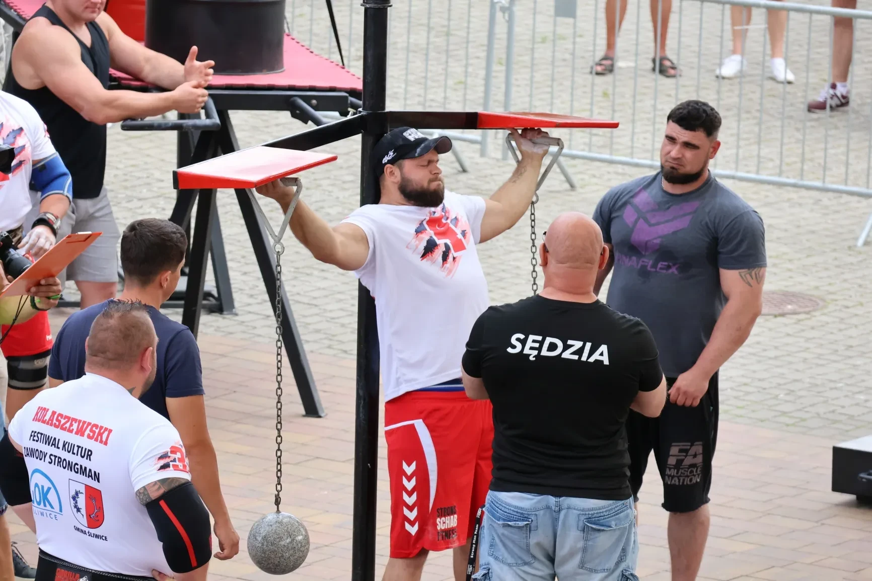 Kulturyści i sedzia.