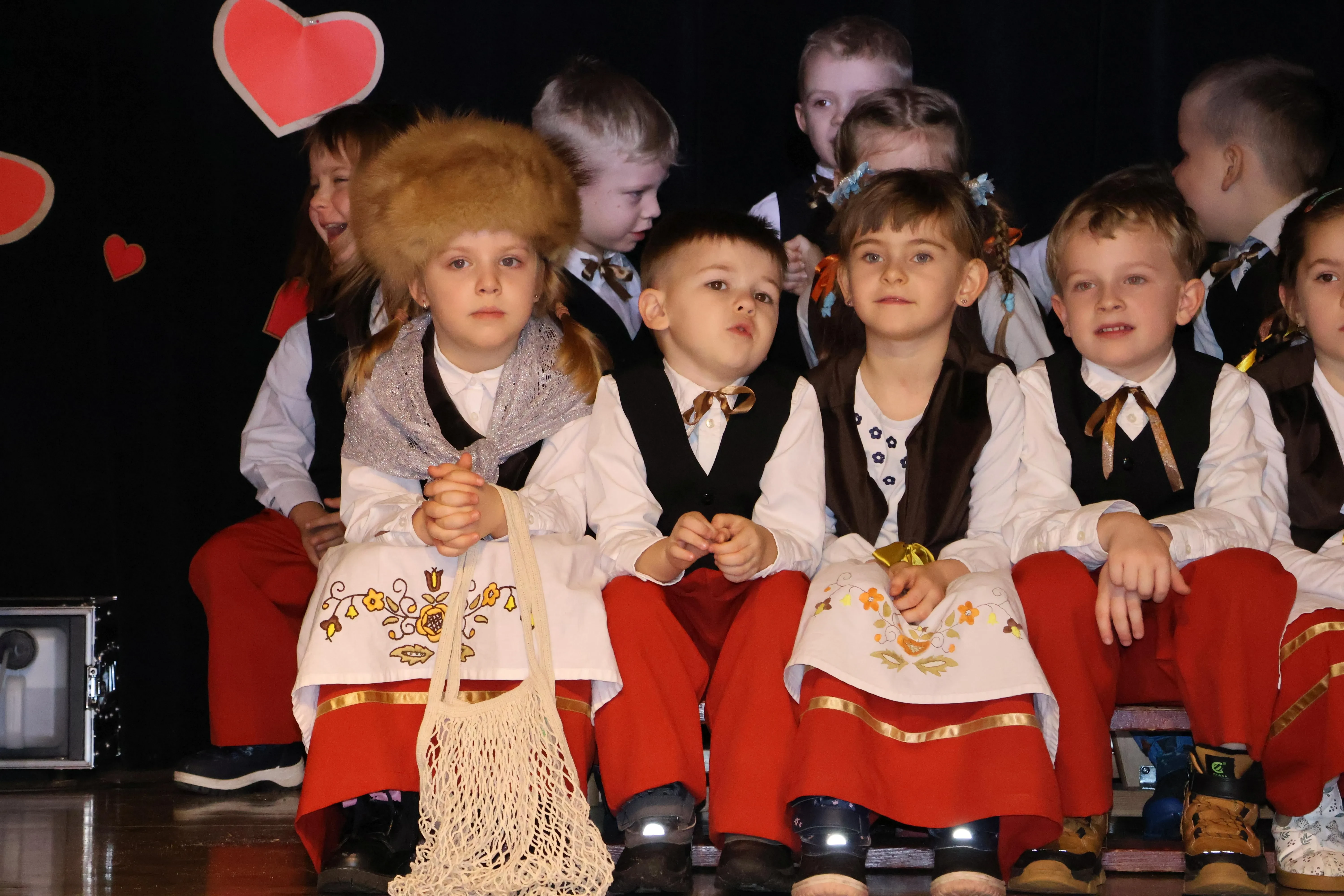 dzieci siedzą na ławeczkach