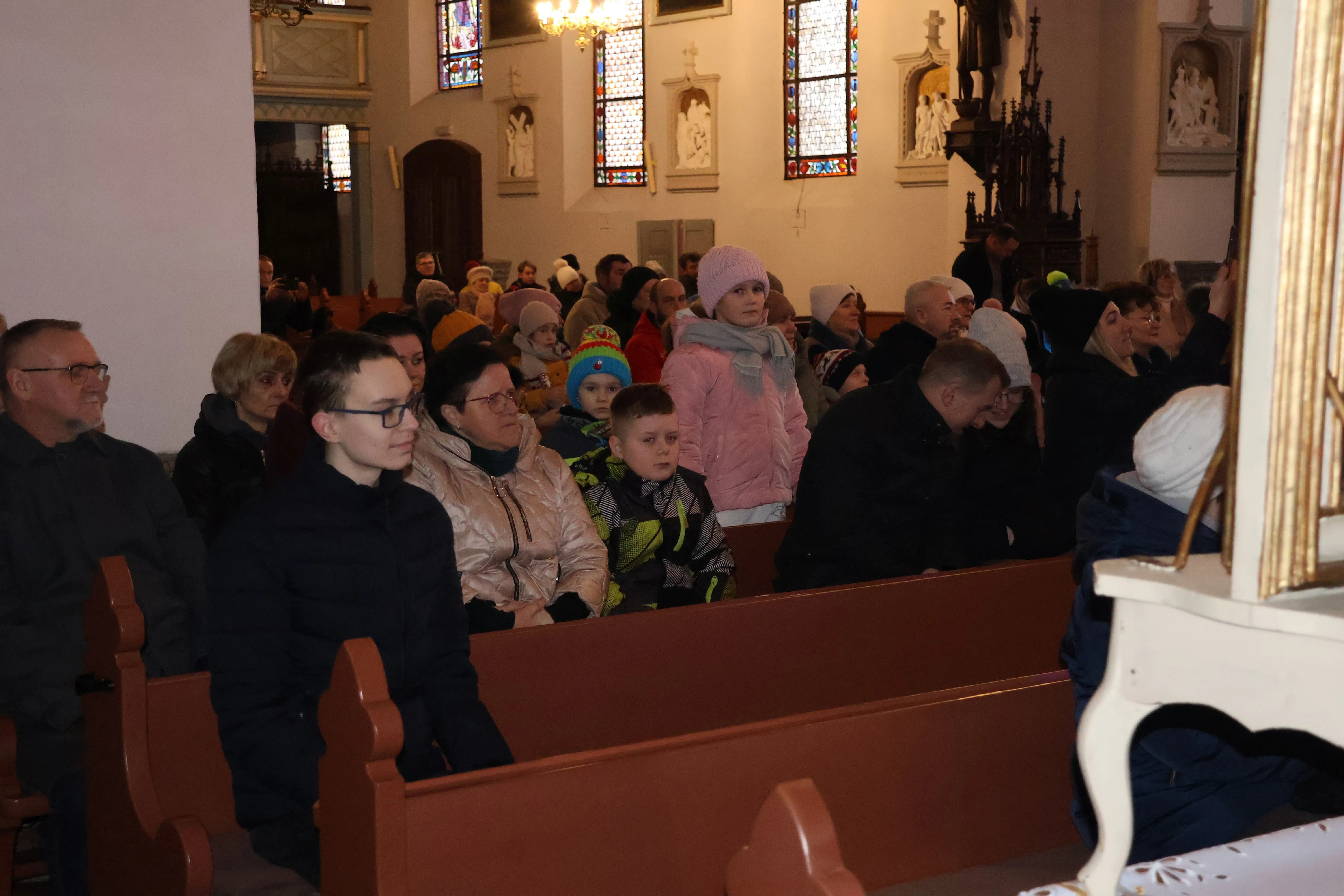 Osoby siedzą w ławkach