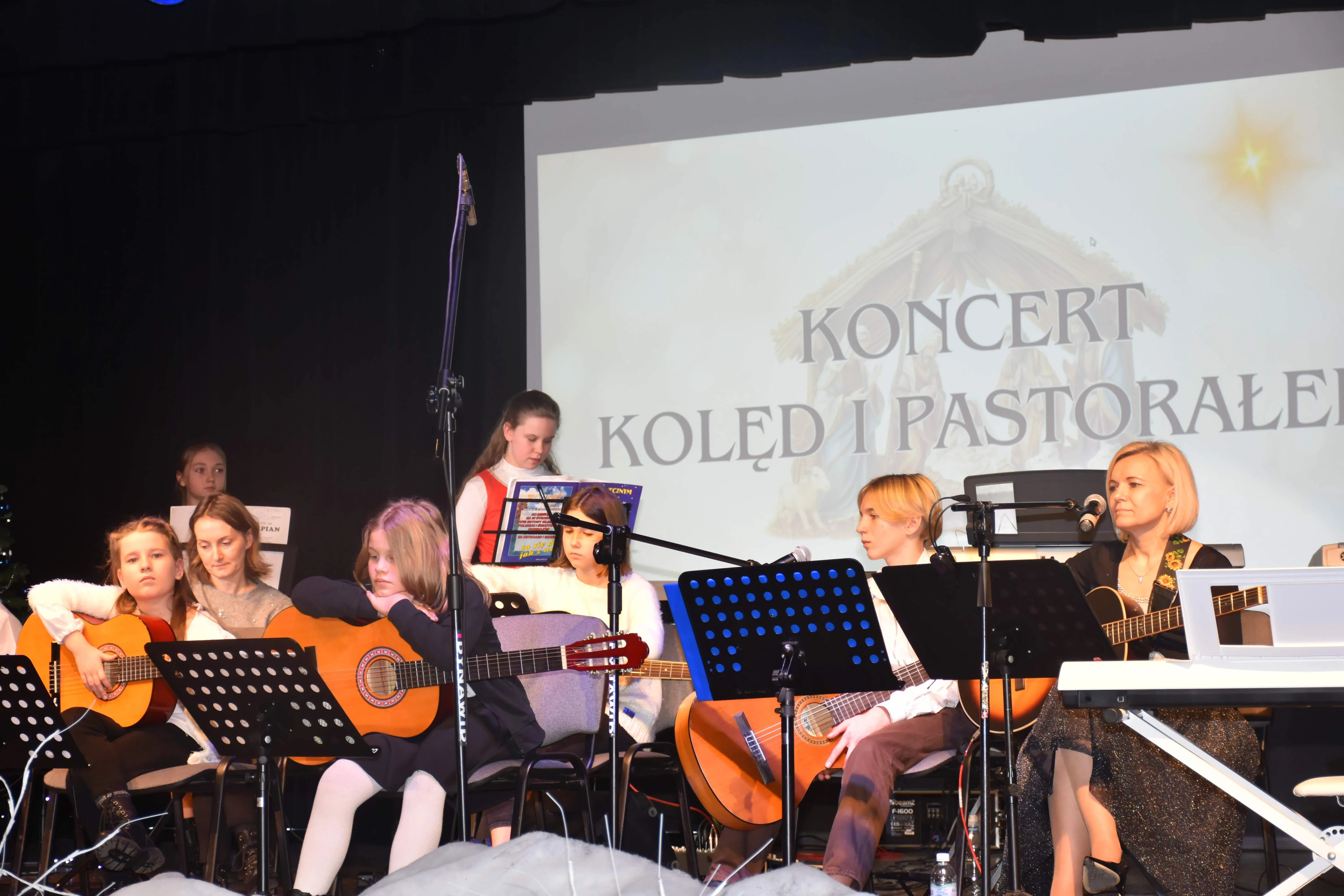 dziewcyzna gra na keyboardzie, w tle napis koncert kolęd i pastorałek