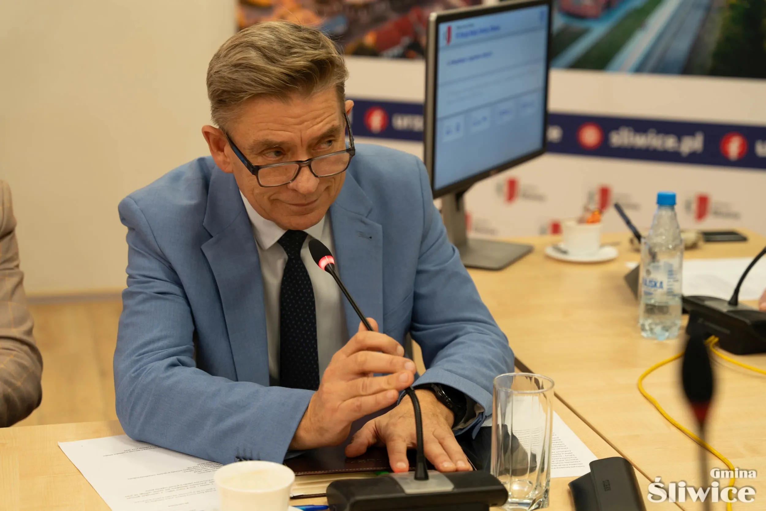 sekretarz gminy uśmiecha się mówiąc do mikrofonu