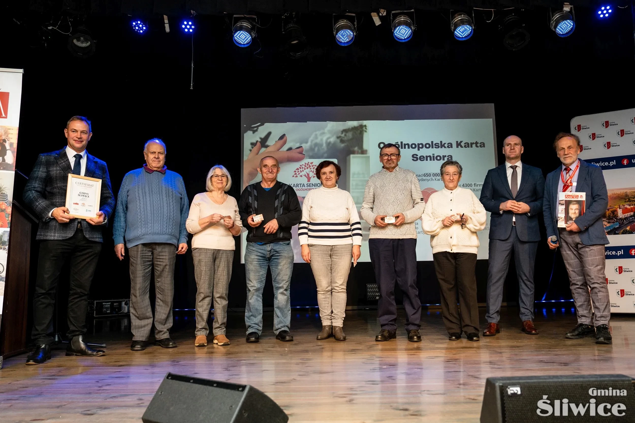 seniorzy z kartami na scenie