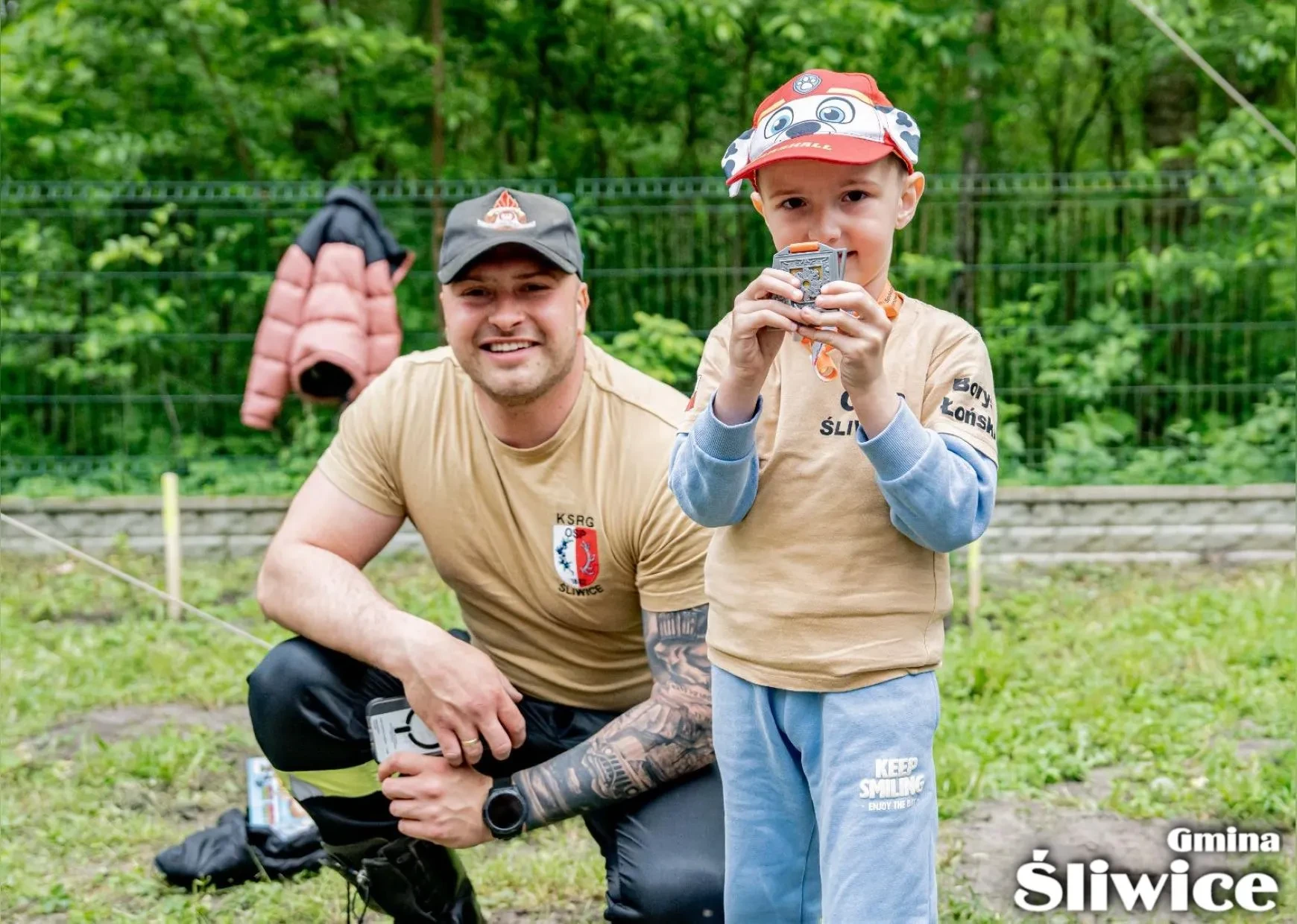 chłopiec z medalem, w tle strażak