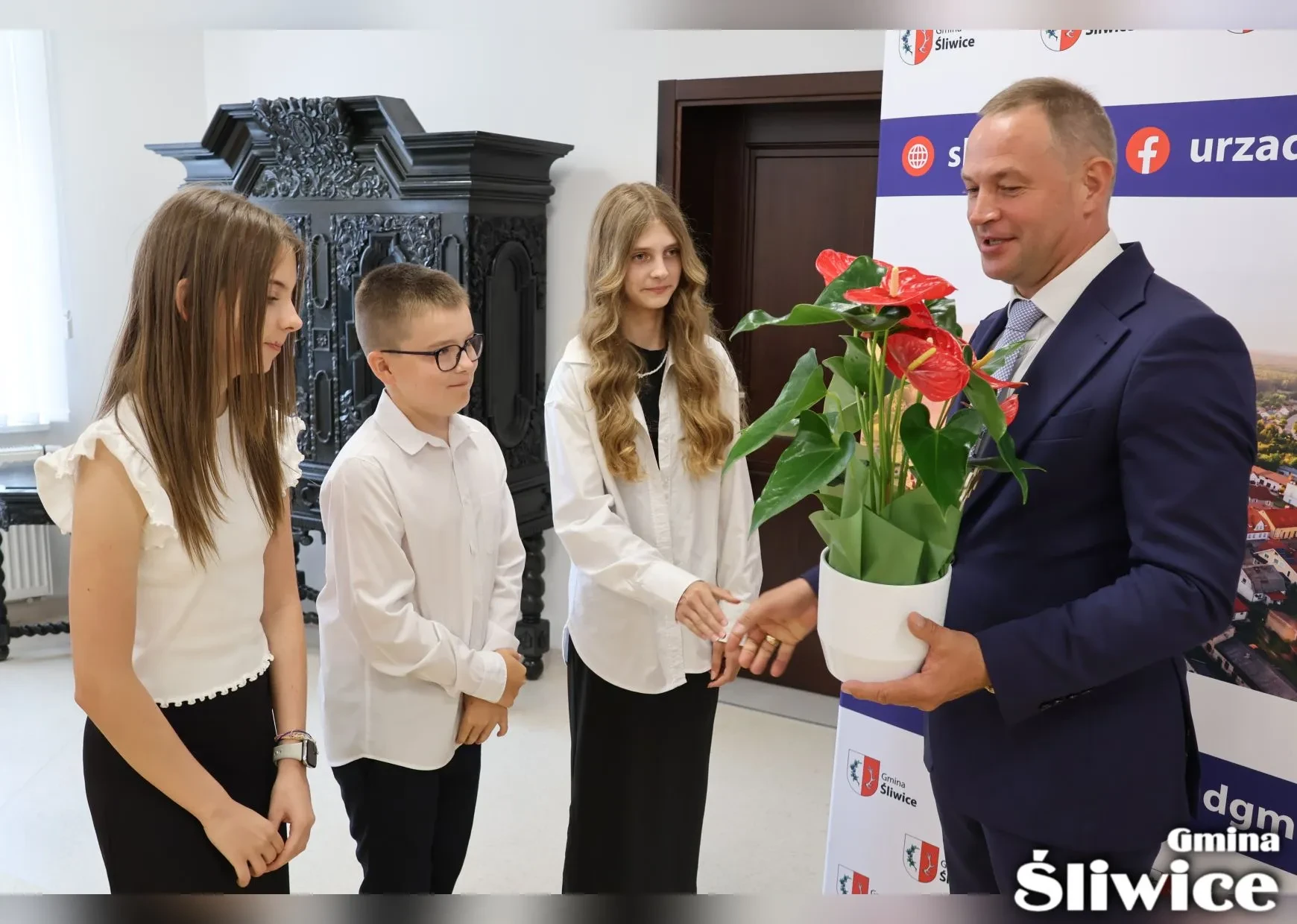 wójt otrzymuje kwiat w doniczce od uczniów