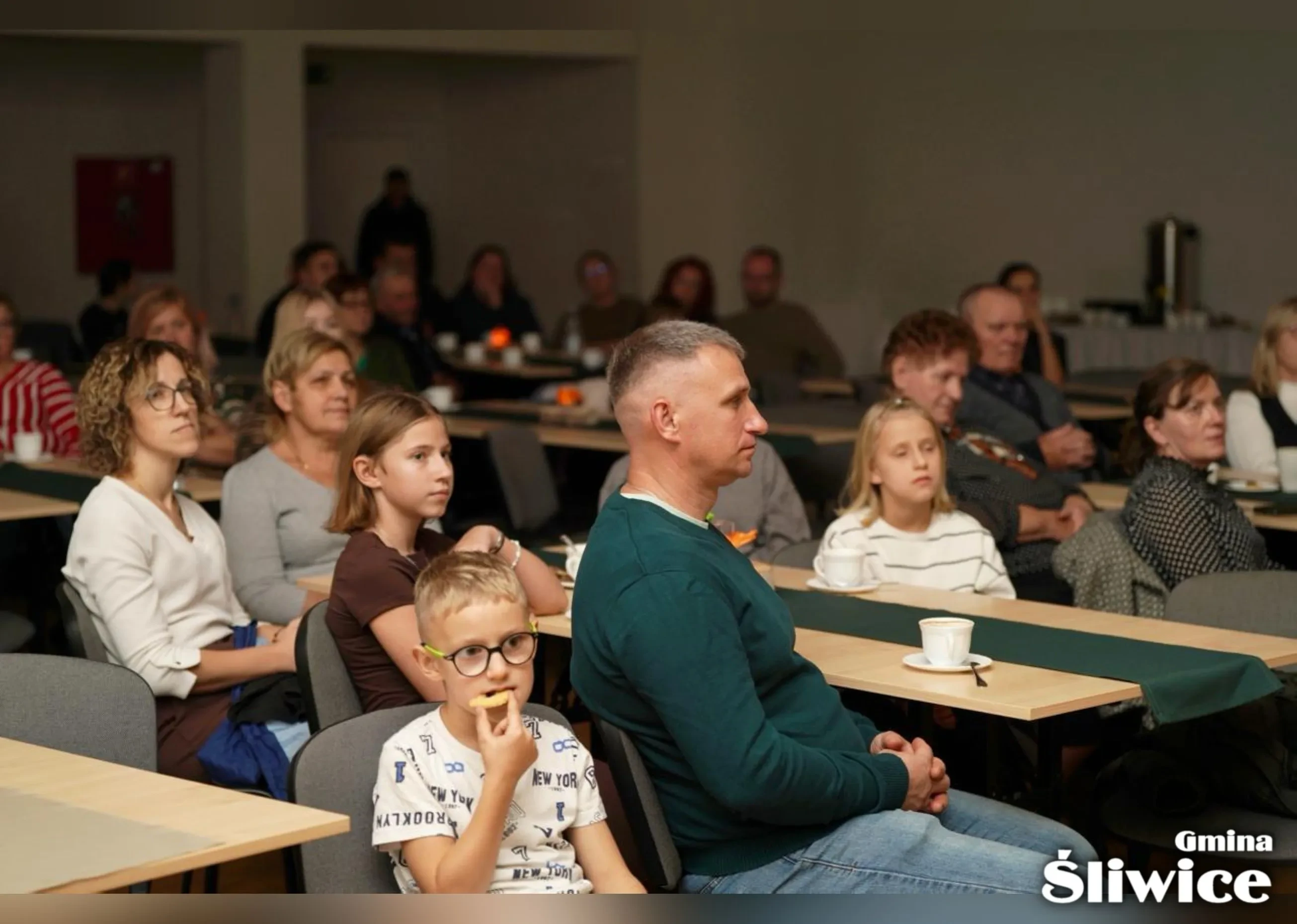 rodzice z dziećmi siedzą przy stołach