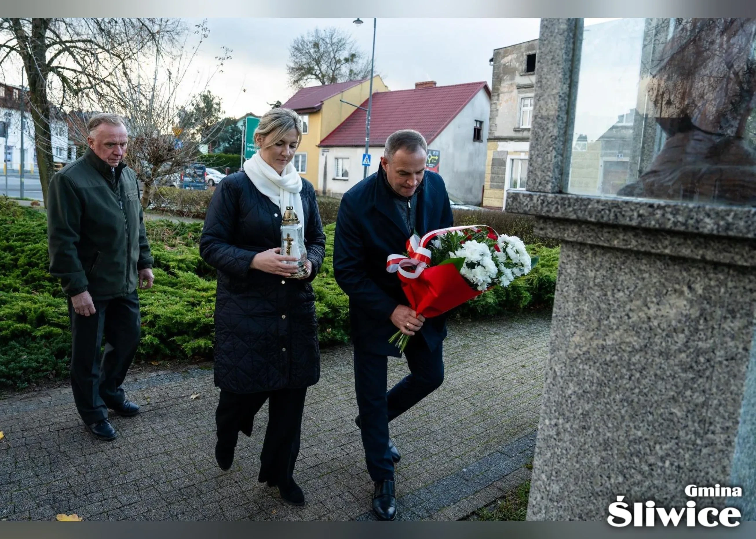 wójt i wicewójt składają kwiaty i znicz przed pomnikiem