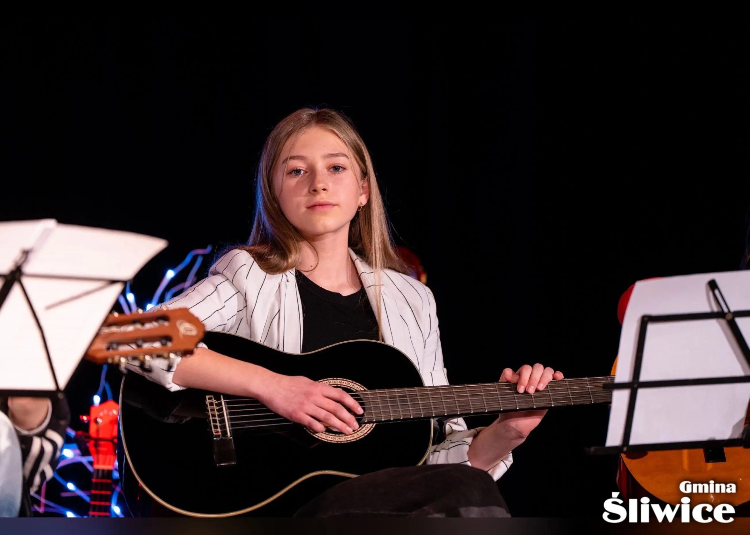 dziewczyna siedzi i trzyma gitarę