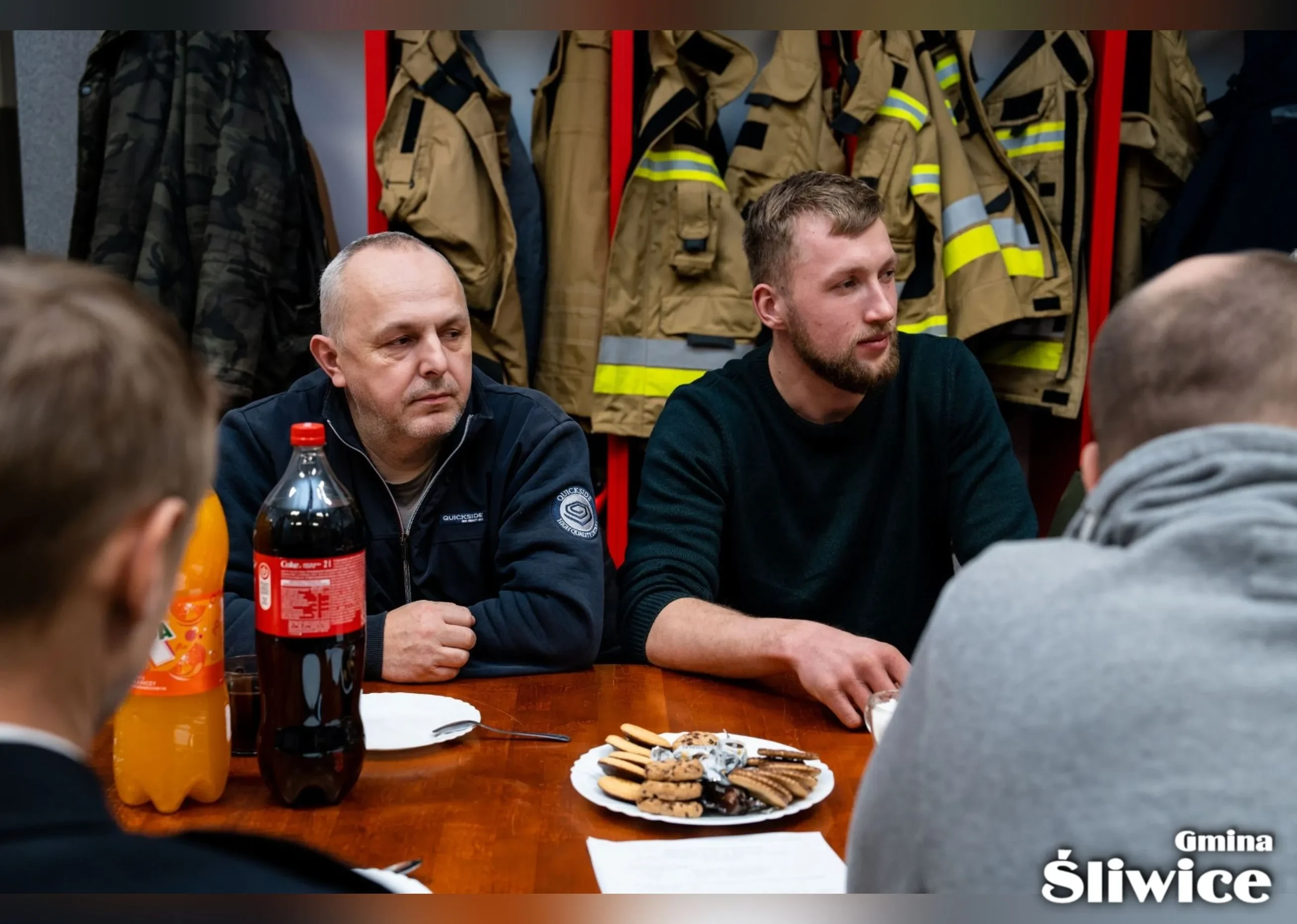 mężczyźni przy stołach patrzą na prowadzącego