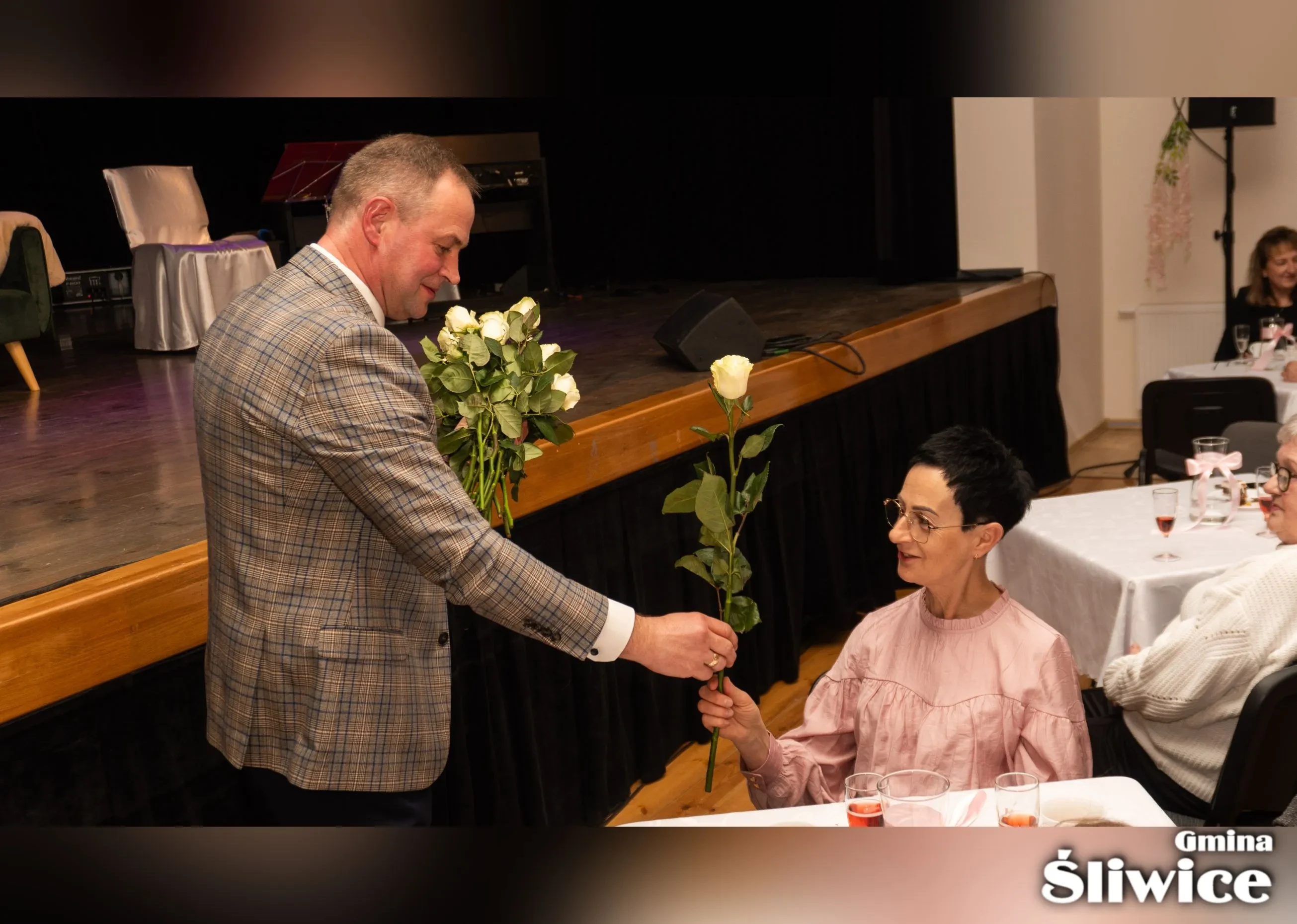 wójt przy scenie przekazuje kwiaty