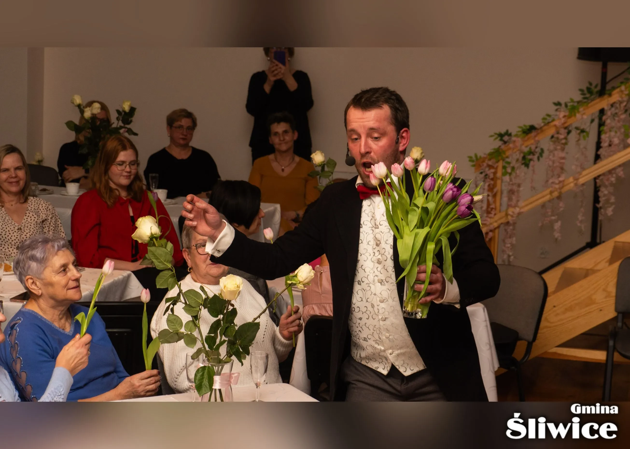 mężczyzna podczas występu rozdaje kwiaty