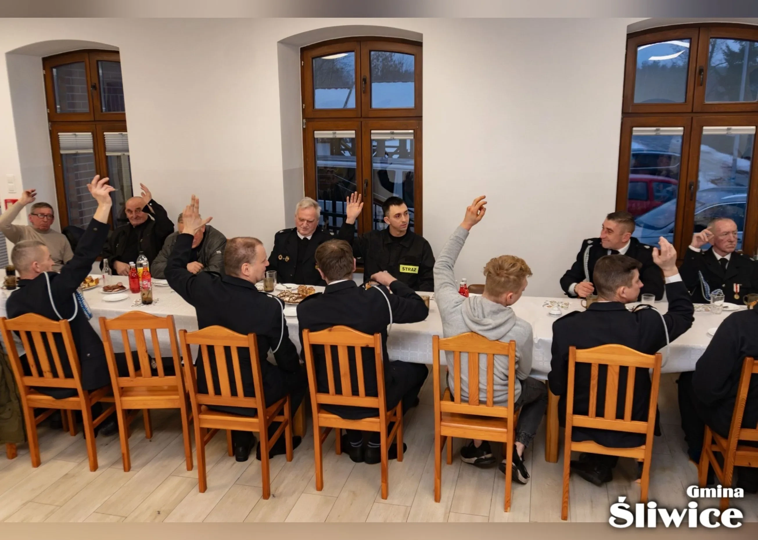 zebrani na sali głosują przez podniesienie ręki