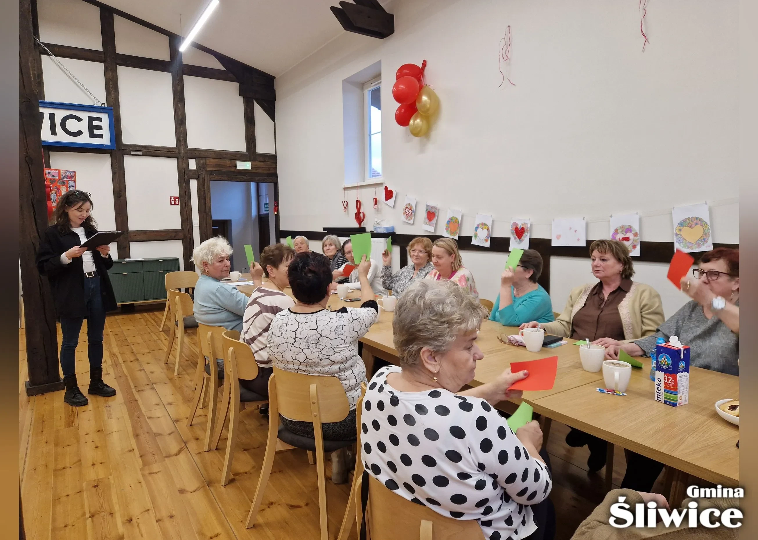 prowadząca czyta, zebrani podnoszą kolorowe kartki